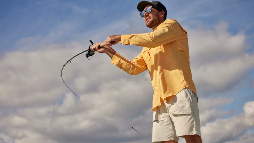 Angler casting in Wrangler ATG gear under an open sky